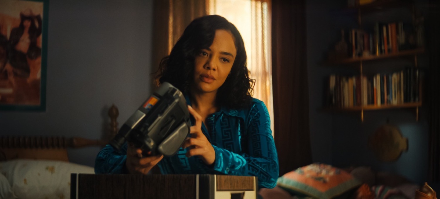 Tessa Thompson in a teal patterned blouse holding a camcorder, His and Hers